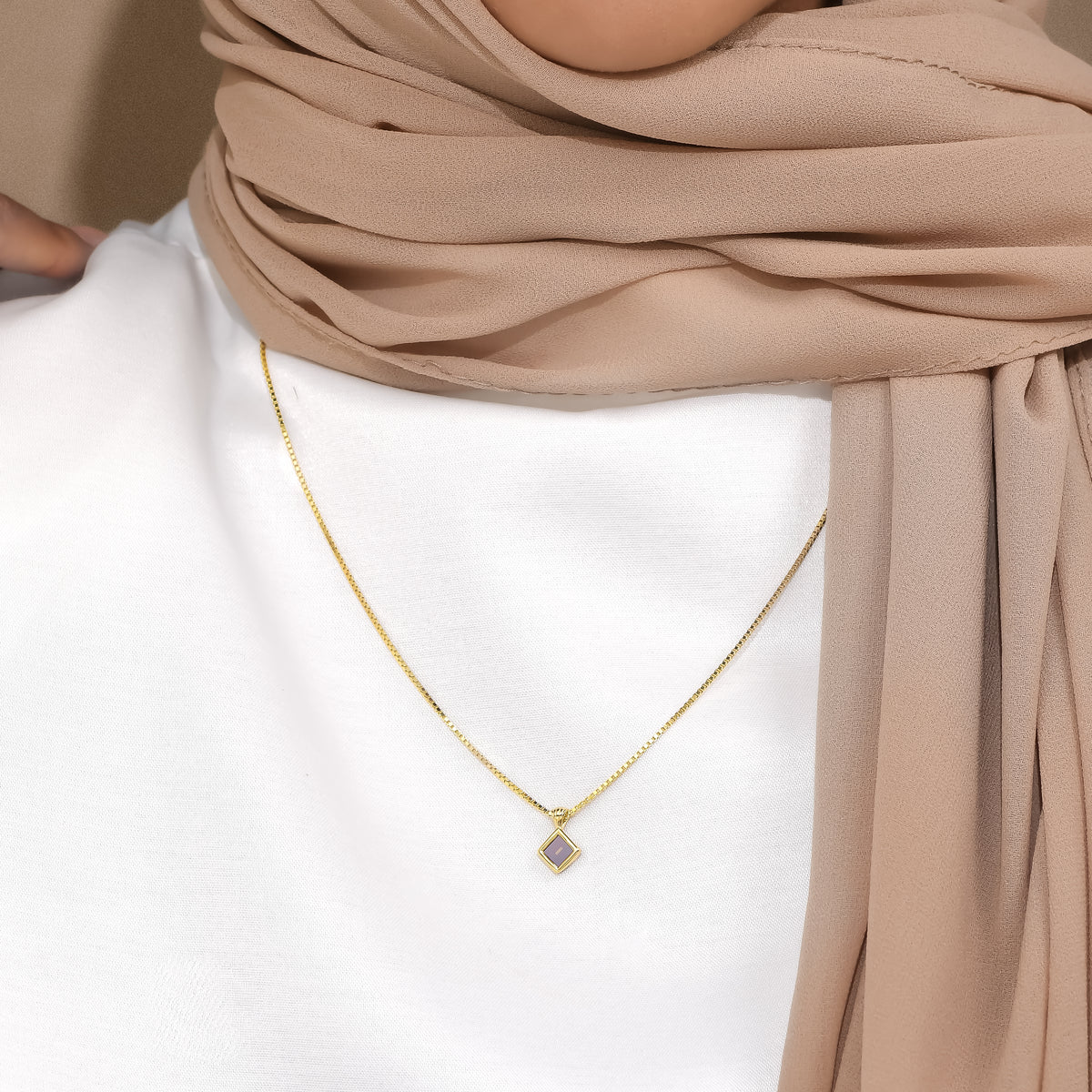Essential petite square pendant worn with a white top and beige scarf