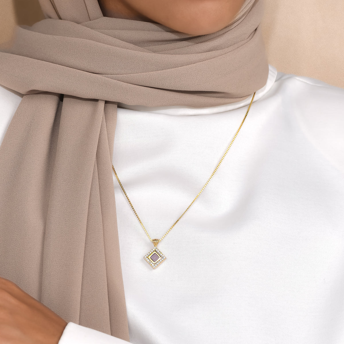 Noor framed square pendant worn with a white top and beige scarf