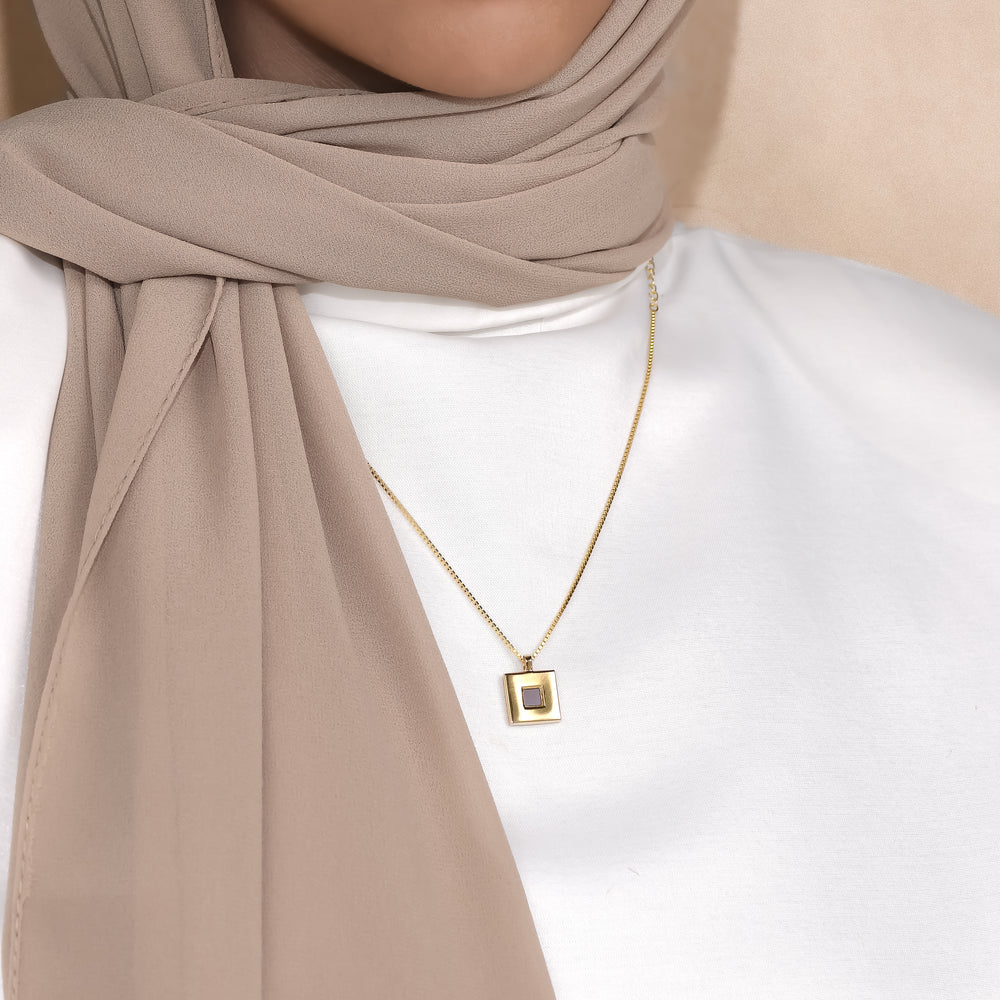 Keepsake open square pendant worn with a white top and beige scarf