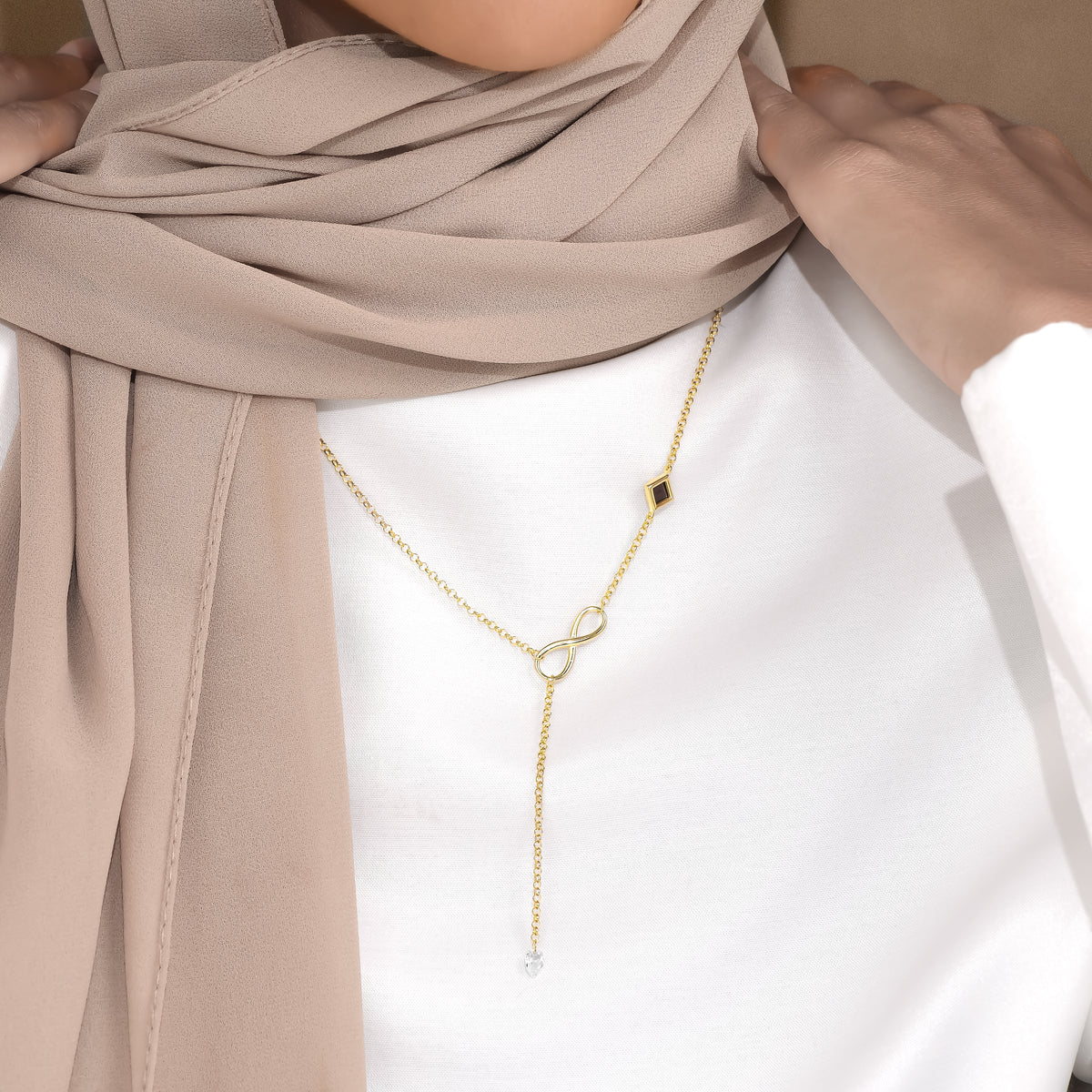 Bond infinity drop necklace worn with a white top and beige scarf